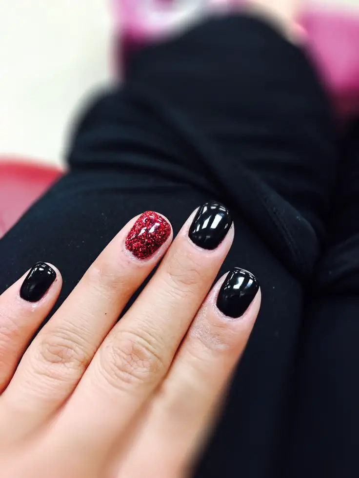 Black gel with red glitter on ring finger on natural nails