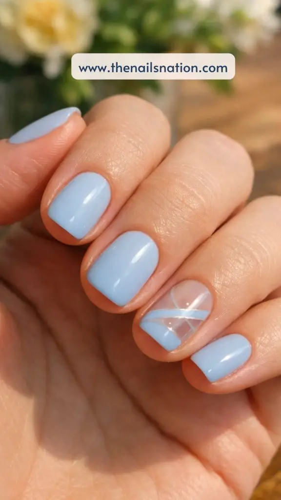 girl casual nail photo, short nails soft blue base with tiny pearl accents on accent fingers, natural spring daylight, hand on white surface with small flowers blurred, realistic everyday shot
